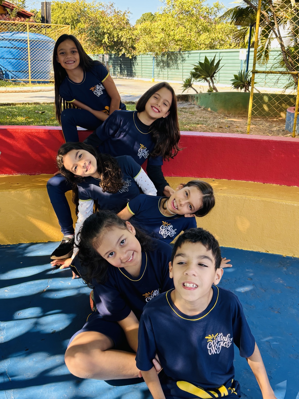 Turma do Ensino Fundamental I reunida e sorrindo no pátio da escola, com o uniforme do Cantinho Mágico